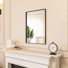 a clock sitting on top of a mantle next to a mirror and fireplace mantel