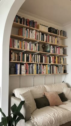 a white couch sitting in front of a book shelf filled with books on top of it