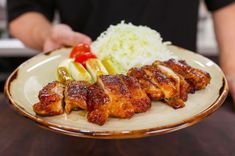 a person holding a plate with chicken and vegetables