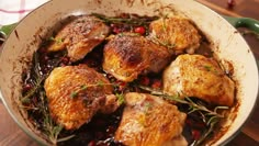 a pan filled with chicken and cranberry sauce on top of a wooden table