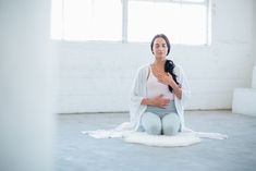 a woman sitting on the floor with her stomach exposed