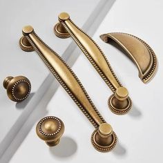 an assortment of antique style handles and knobs on a white surface with gold accents