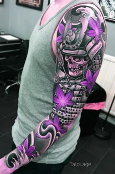 a man's arm with purple flowers and a skull in the center on it