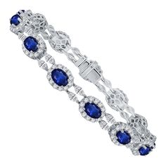 Elevate your jewelry collection with this exceptional bracelet, a true embodiment of timeless beauty and sophistication. It features thirteen resplendent oval-cut blue sapphires, collectively weighing 9.42 carats, each delicately framed by a halo of round diamonds. This combination of sapphires and diamonds evokes a sense of royalty, wisdom, and eternal love. Interspersed between the sapphires are pairs of marquise-cut diamonds, adding a touch of creativity and balance to the design. The combine Luxury Oval Sapphire Tennis Bracelet, Blue Oval Diamond Bracelet With Jewels, Luxury Blue Oval Diamond Bracelet, Blue Oval Diamond Bracelet With Gemstone, Oval Sapphire Diamond Bracelet, Formal Sapphire Oval Bracelets, Formal Blue Oval Diamond Bracelet, Oval Sapphire Bracelet In White Gold, Oval Sapphire Bracelets In White Gold