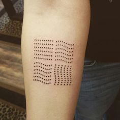 a person with a tattoo on their arm that has dots in the shape of letters