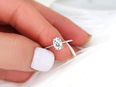 a woman's hand with a ring on her finger and a diamond in the middle