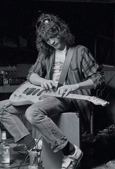 a man with long hair playing an electric guitar