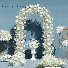 white flowers and greenery are arranged in front of an arch