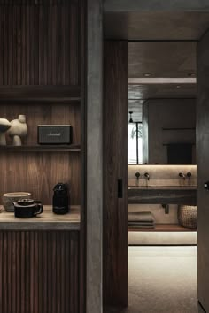 an open door leading to a bathroom with wood paneling and shelves filled with items