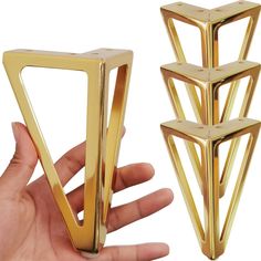 a hand is holding three gold geometric objects