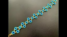 a beaded bracelet with blue and yellow beads on a black surface, in the shape of a flower