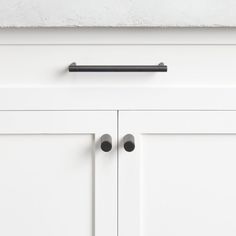 a white cabinet with black handles and knobs