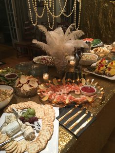 an assortment of food is displayed on a table with candles, plates and utensils