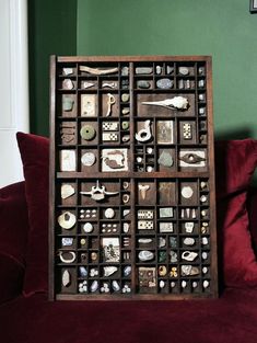 a wooden box filled with lots of assorted items on top of a red couch