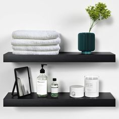 two black shelves with towels, soaps and other items on them next to each other