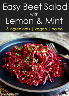 beet salad with lemon and mint on a black plate next to a silver fork