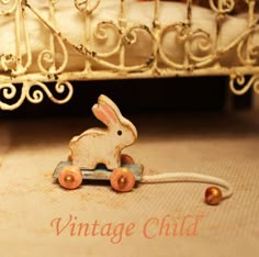 a toy rabbit is sitting on the floor next to a bed with an iron frame