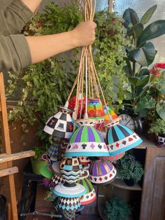 a person is holding up some colorful lights in front of plants and potted plants