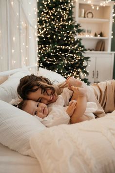 a woman laying on top of a bed next to a christmas tree