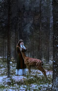 a woman standing next to a deer in the woods