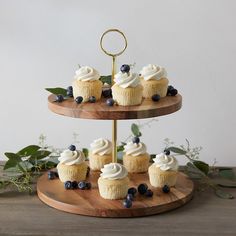 cupcakes with white frosting and blueberries on a wooden platter