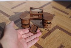 a hand is holding a small wooden table with two drawers and a mirror on it