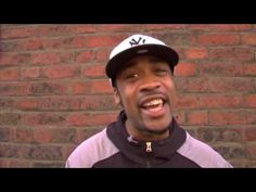 a man wearing a baseball cap standing in front of a brick wall with his mouth open