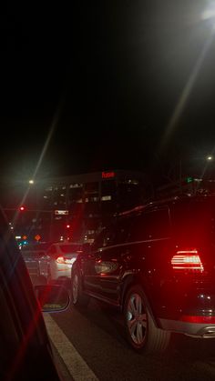 cars are parked on the side of the road at night with street lights shining in the background