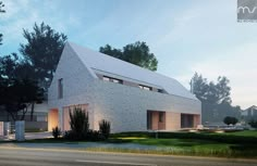 a white brick house sitting on the side of a road next to a lush green field