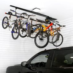 three bikes are hanging from the ceiling above a car