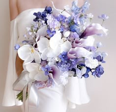 a bride holding a bouquet of purple and white flowers