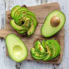 an avocado sandwich cut in half on a cutting board