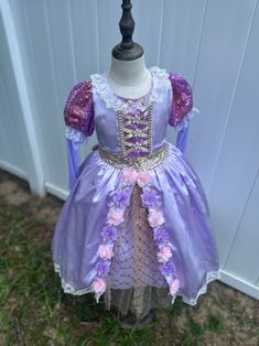 Transform your little one into a fairy tale princess with this enchanting lilac dress, perfect for special occasions and dress-up play. Crafted with love and meticulous attention to detail, this dress is sure to make dreams come true. ✨ **Features 🌸 **Elegant Design Lavish lilac satin fabric adorned with delicate lace and floral accents. 💫 **Sparkling Details Glittery sequin puff sleeves add a touch of magical sparkle. 🎀 **Lace-Up Bodice Intricate lace-up front with pearl embellishments for a Lavender Princess Dress For Wedding, Lavender Princess Dress For Dress-up, Lavender Princess Dress For Dress-up Occasions, Lavender Fitted Princess Dress For Dress-up, Lavender Tulle Dress For Dress-up, Lavender Tulle Dress For Dress-up Occasions, Fairy Style Purple Wedding Dresses, Purple Fairy Style Wedding Dress, Purple Fairy Wedding Dresses