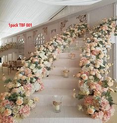 a set of white and pink flowers on the side of a long table in a room