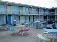 several tables and benches in front of an apartment building