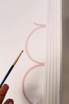 a person holding a pencil in front of a wall with the number 3 painted on it