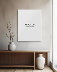 a white vase sitting on top of a wooden table next to a wall mounted poster