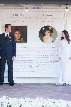 a man and woman standing in front of a white banner with flowers on it,