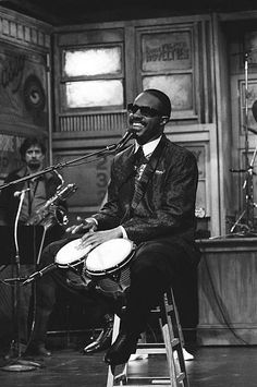 a man sitting on top of a stool next to a microphone and playing the drums