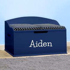 a blue toy box with the name aiden on it sitting in front of a wall