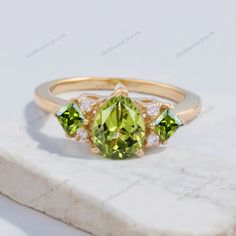 Pear Peridot Cluster Wedding Ring 18K Yellow Gold Rings Alternative Fine Jewelry August Birthstone Gifts Delicate Art Deco Anniversary Rings Description: Main Stone - Peridot ( Lab Created ) Stone Size - 7 x 5 mm / 3 MM Stone color - Green Stone shape - Pear / Princess Cut Birthstone: August Secondary Stone : CZ Diamond Stone Shape : Round Stone Color : Colorless Finishing- Excellent feel free to contact me if you have any questions  Gemstone color may slightly vary from listed image due to the nature of all natural gemstone or different monitor settings TURNAROUND TIME Your order will be ready for shipment in 4-8 business days. Free economy shipping for US, UK, Germany- 10-15 business days delivery time. shipping upgrade available for US, UK, Germany- 5-7 business days delivery time. Plea Elegant Peridot Birthstone Ring For Wedding, Elegant Peridot Wedding Birthstone Ring, Anniversary Peridot Diamond Ring, Peridot Diamond Ring With Gemstone For Anniversary, Peridot Birthstone Ring For Wedding, Fine Jewelry Peridot Diamond Wedding Ring, May Birthstone Wedding Ring In Cubic Zirconia, Fine Jewelry Peridot Diamond Ring For Wedding, Green Birthstone Ring With Center Stone For Wedding