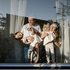 two adults and three children standing in front of a window