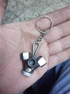 a hand holding a small metal object in it's left hand, with the key chain attached to it