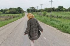 a woman walking down the middle of a road