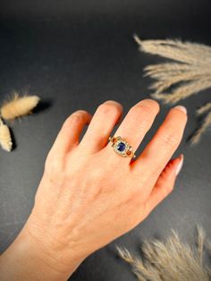 a woman's hand with a ring on it and some dried grass in the background