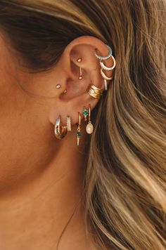 a close up of a person with ear piercings on their ears and wearing gold jewelry