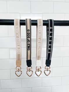 three lanyards hanging from a rail with hearts and words printed on the straps