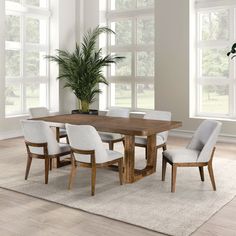 a dining room table with white chairs and a potted plant