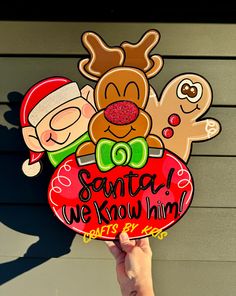 a hand holding up a sign that says santa we know him with reindeers on it