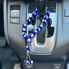 a blue beaded bracelet hanging from the center console of a car